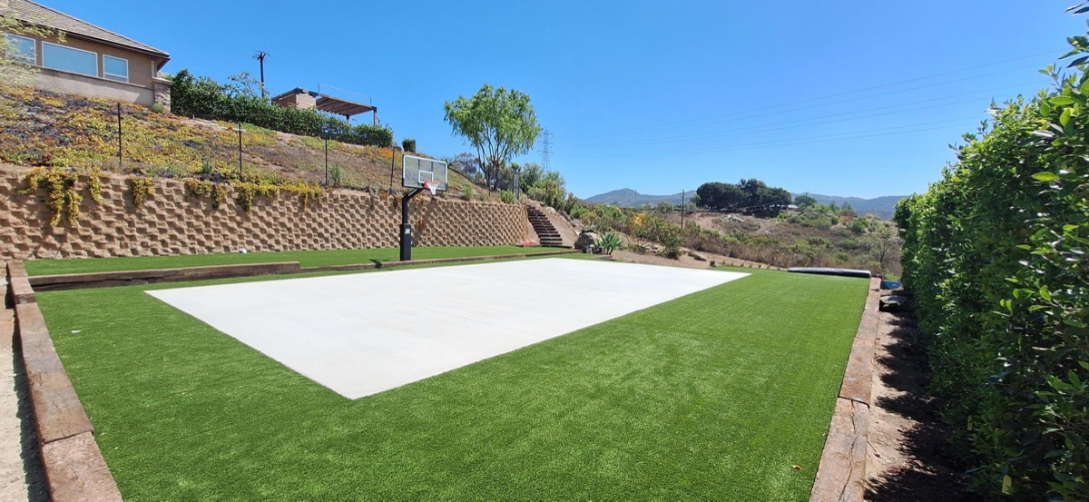 Backyard sport court with basketball hoop surrounded by artificial turf in North County San Diego
