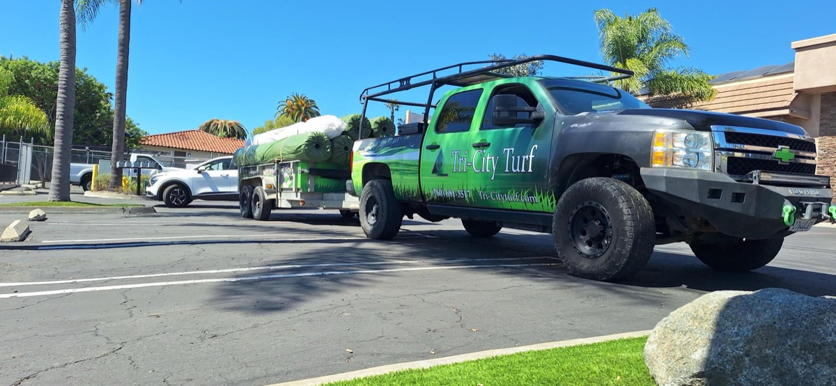 Tri-City Turf branded truck and trailer loaded with turf rolls on a job site in North County San Diego
